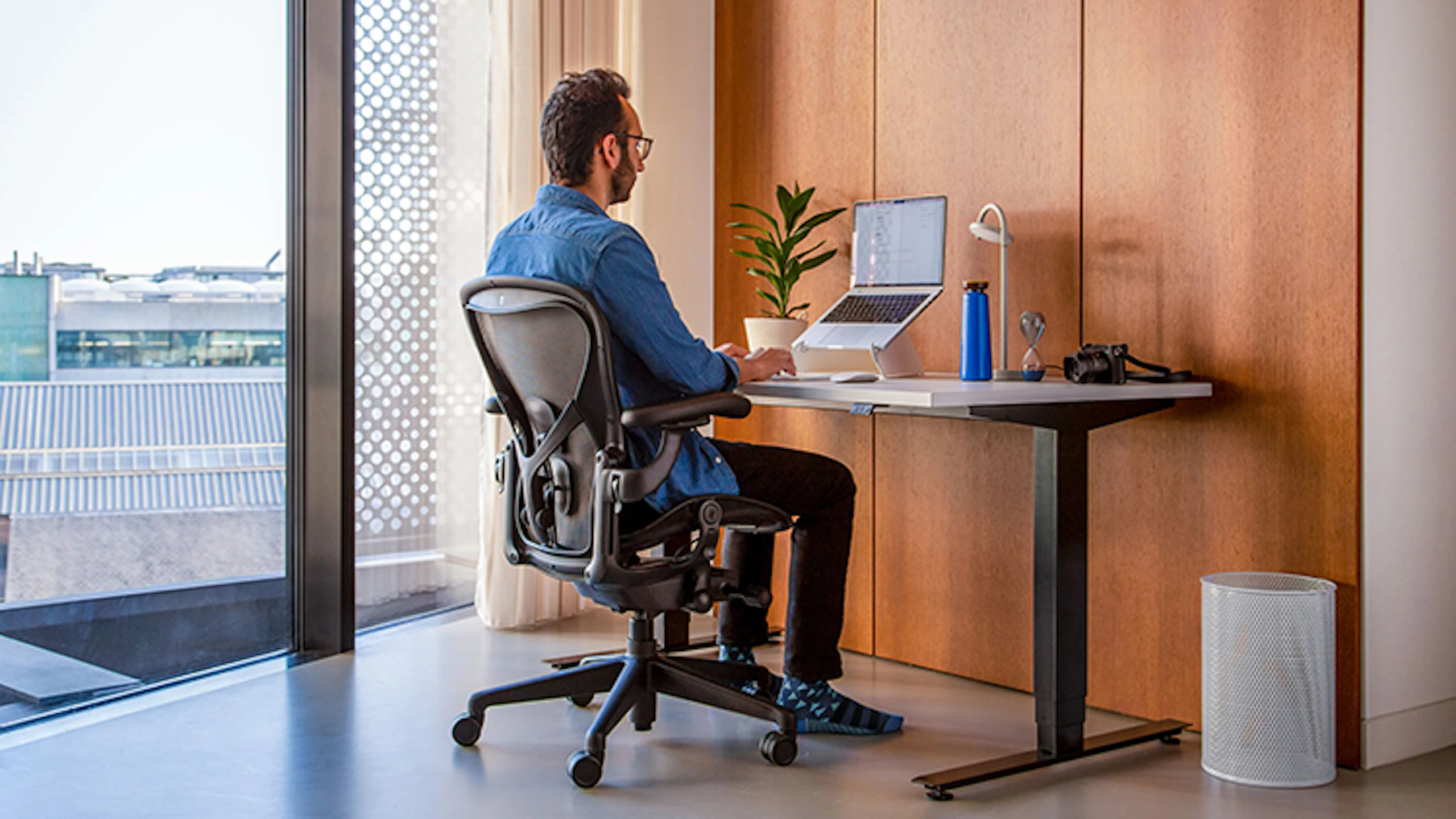 Ali Abdaal shown working at his home office set up in his London apartment.