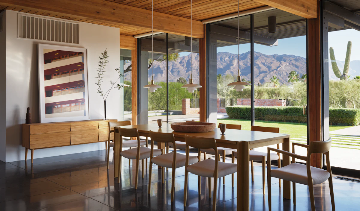Set of wooden dining chairs and table in a glass-walled dining area with mountain view