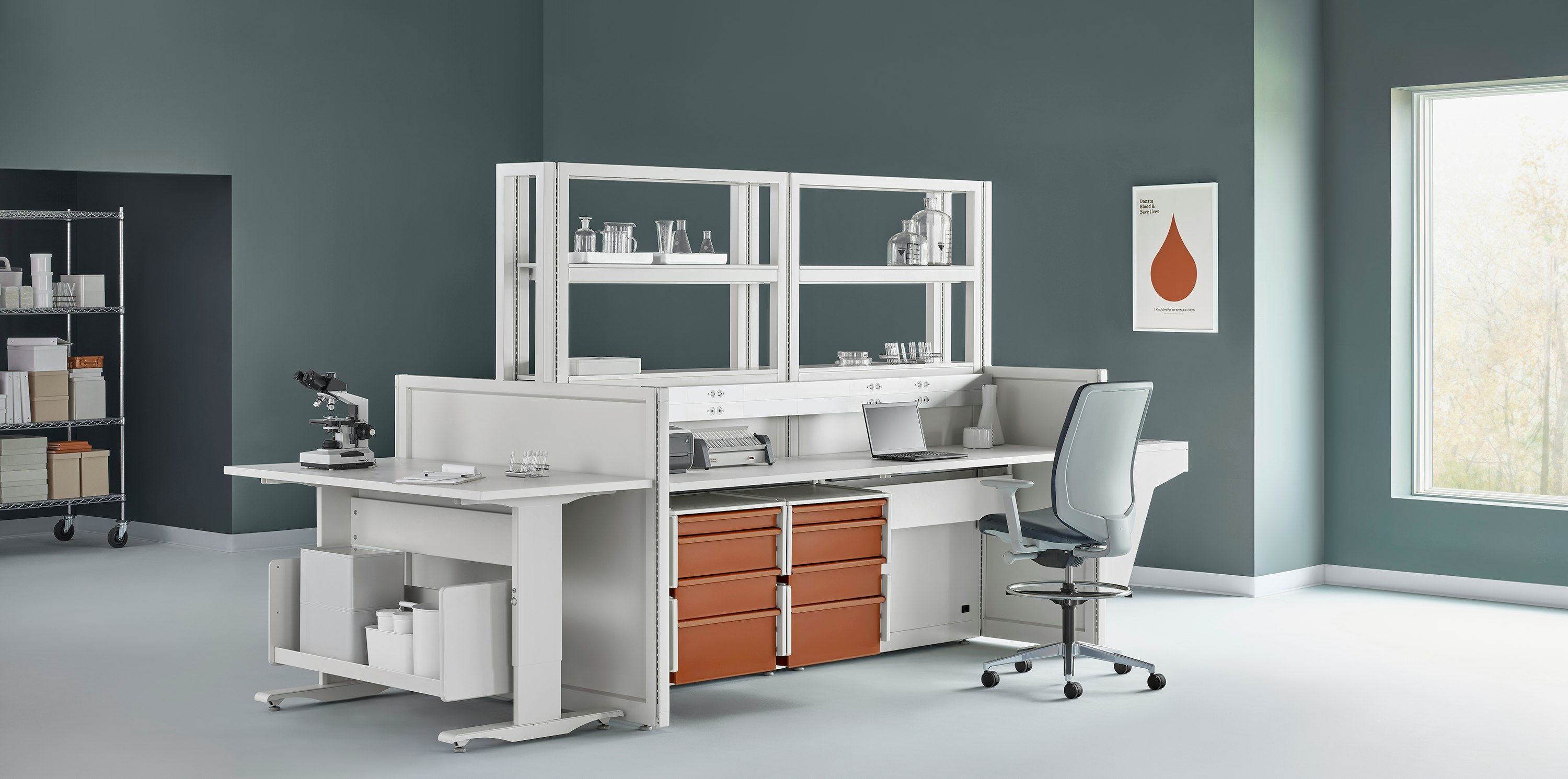 Soft white Co/Struc System with terra cotta storage drawers, various laboratory equipment, and a process table with a dark gray Verus Stool.