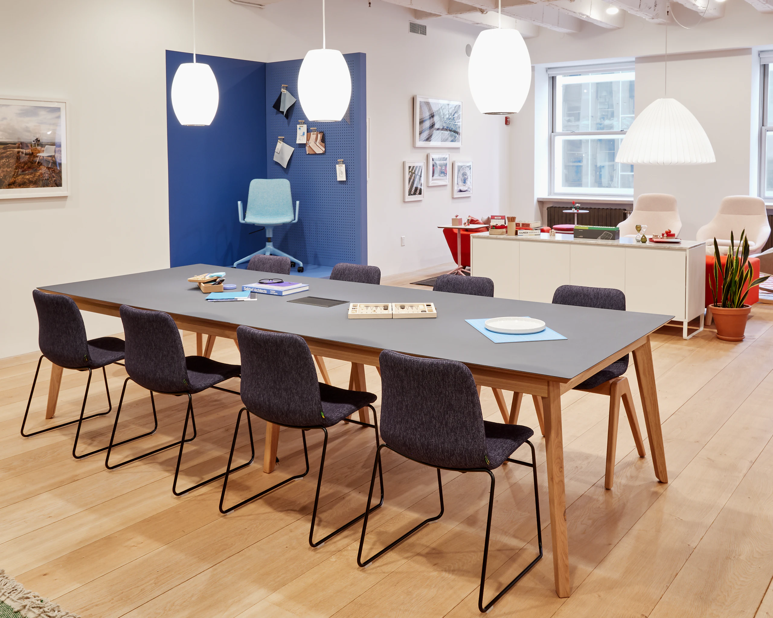 Eight upholstered Viv Chairs with black sled bases, around a large Dalby table.