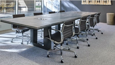 Eight black Eames Aluminum Group Chairs by Herman Miller arranged around a large conference table