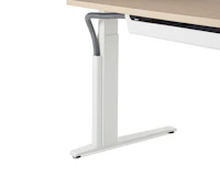 Close up of a mesh vertical wire manager attached to the white leg of a height adjustable table.