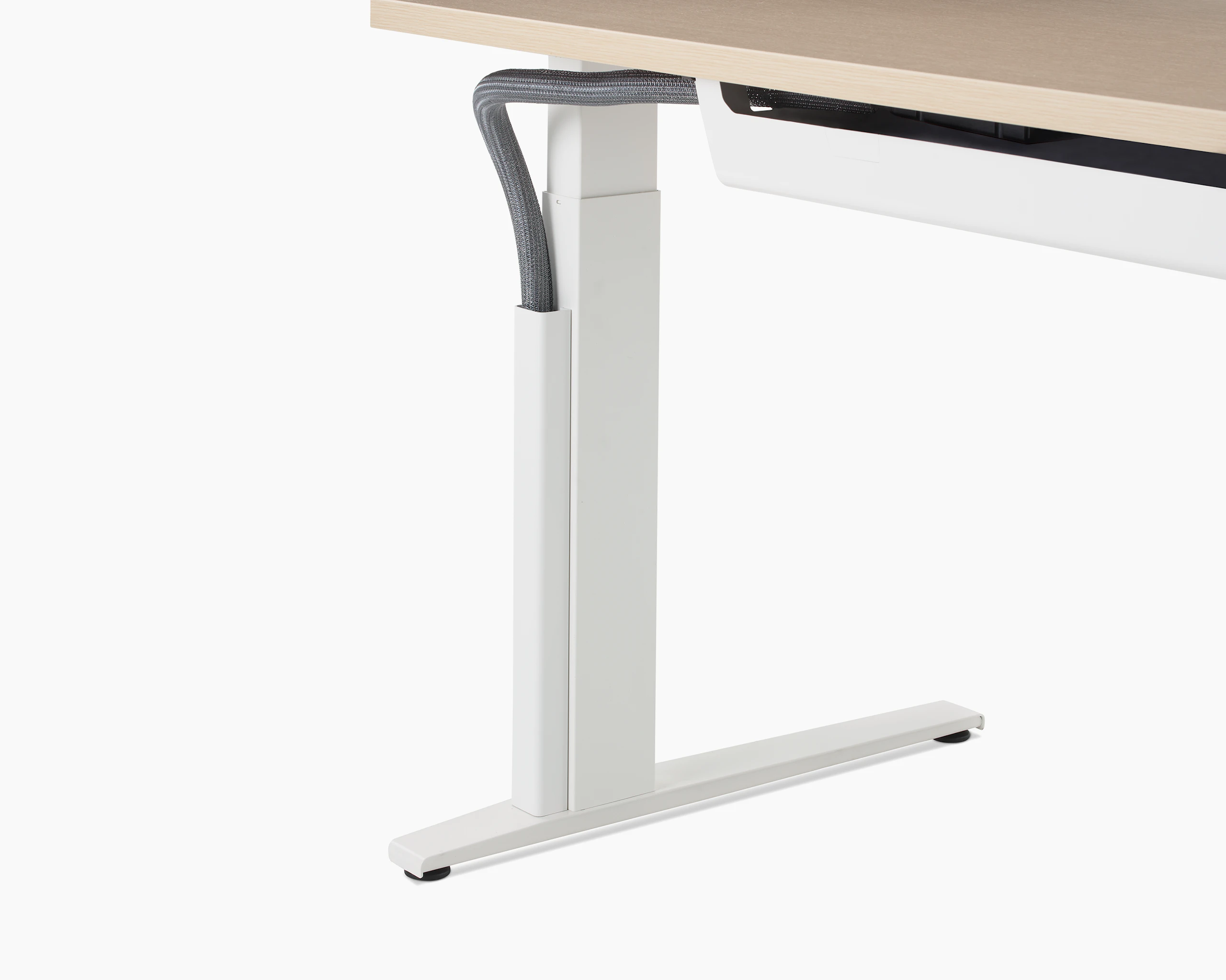 Close up of a mesh vertical wire manager attached to the white leg of a height adjustable table.