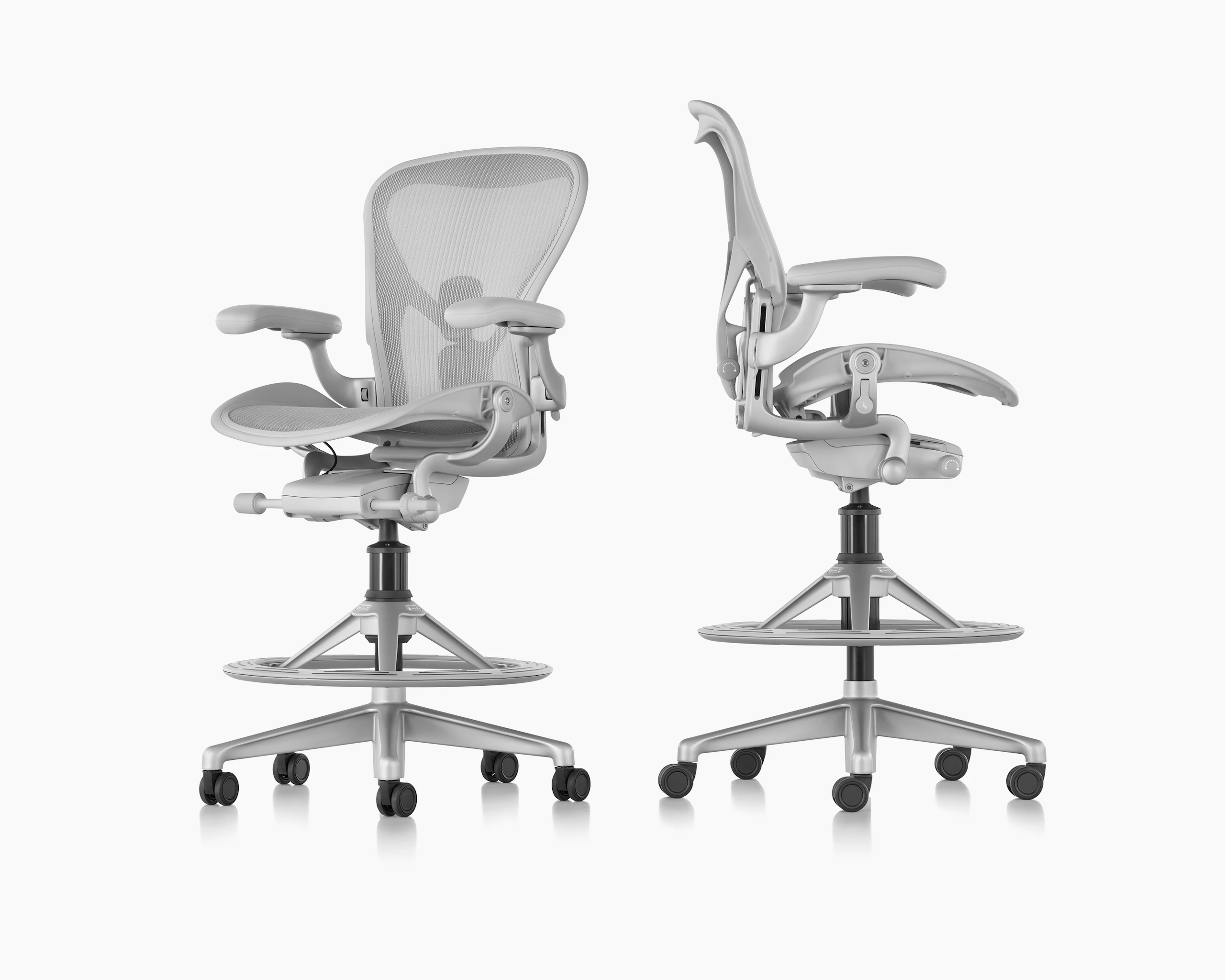 Two Aeron stools in light grey beside each other. One faces forward the other faces sideways.