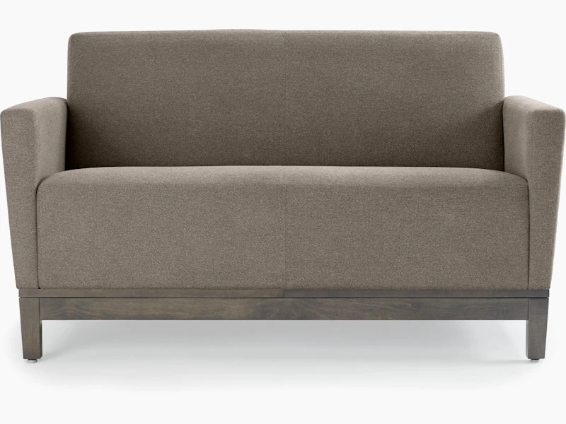 Front view of a gray Brava Platform Lounge System two-seat sofa with upholstered arms on a wood base.