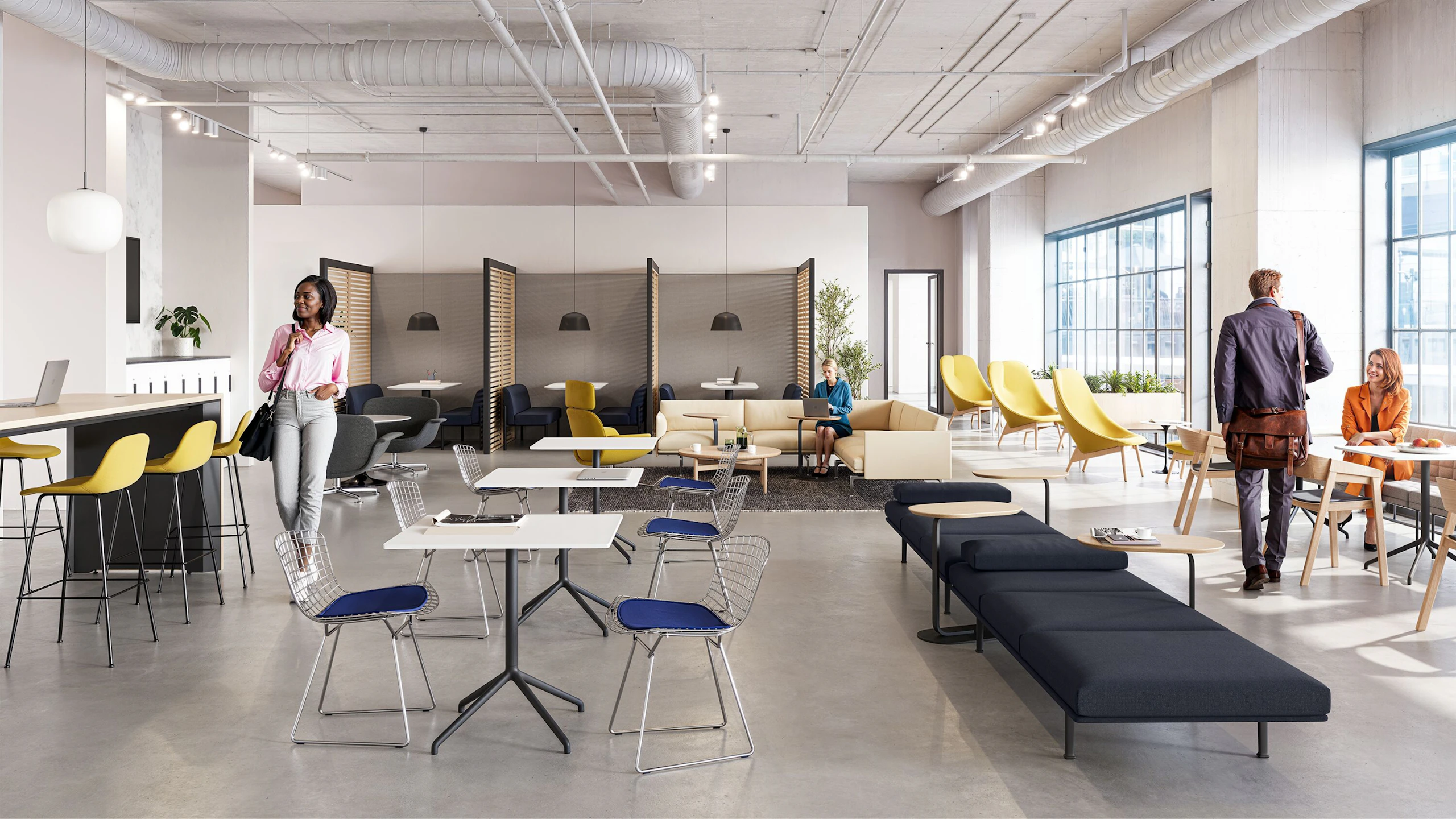 A brightly lit community setting featuring four persons utilizing a variety of colorful seating options including the HAY Uchiwa Lounge Chair, Muuto Base Tables, and Muuto Still Cafe Tables