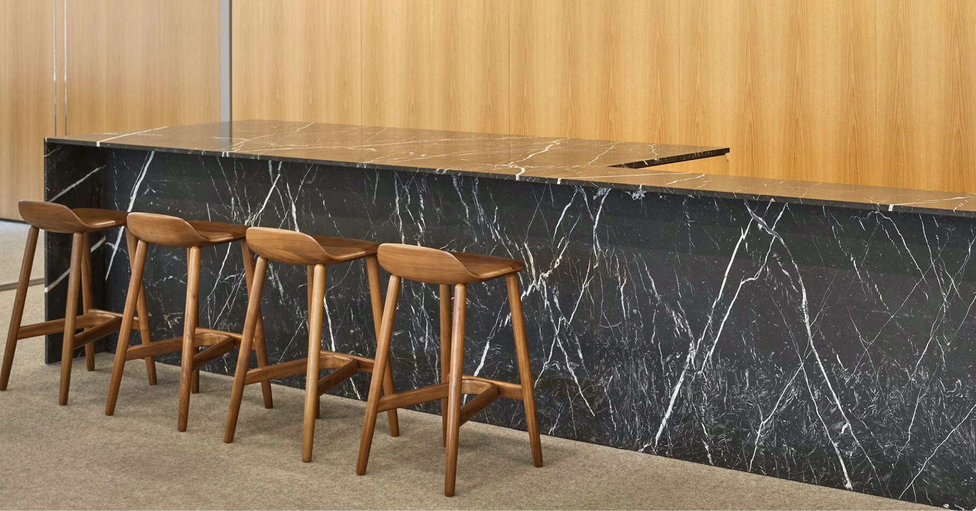 Four brown counter-height stools at a dark grey and white counter