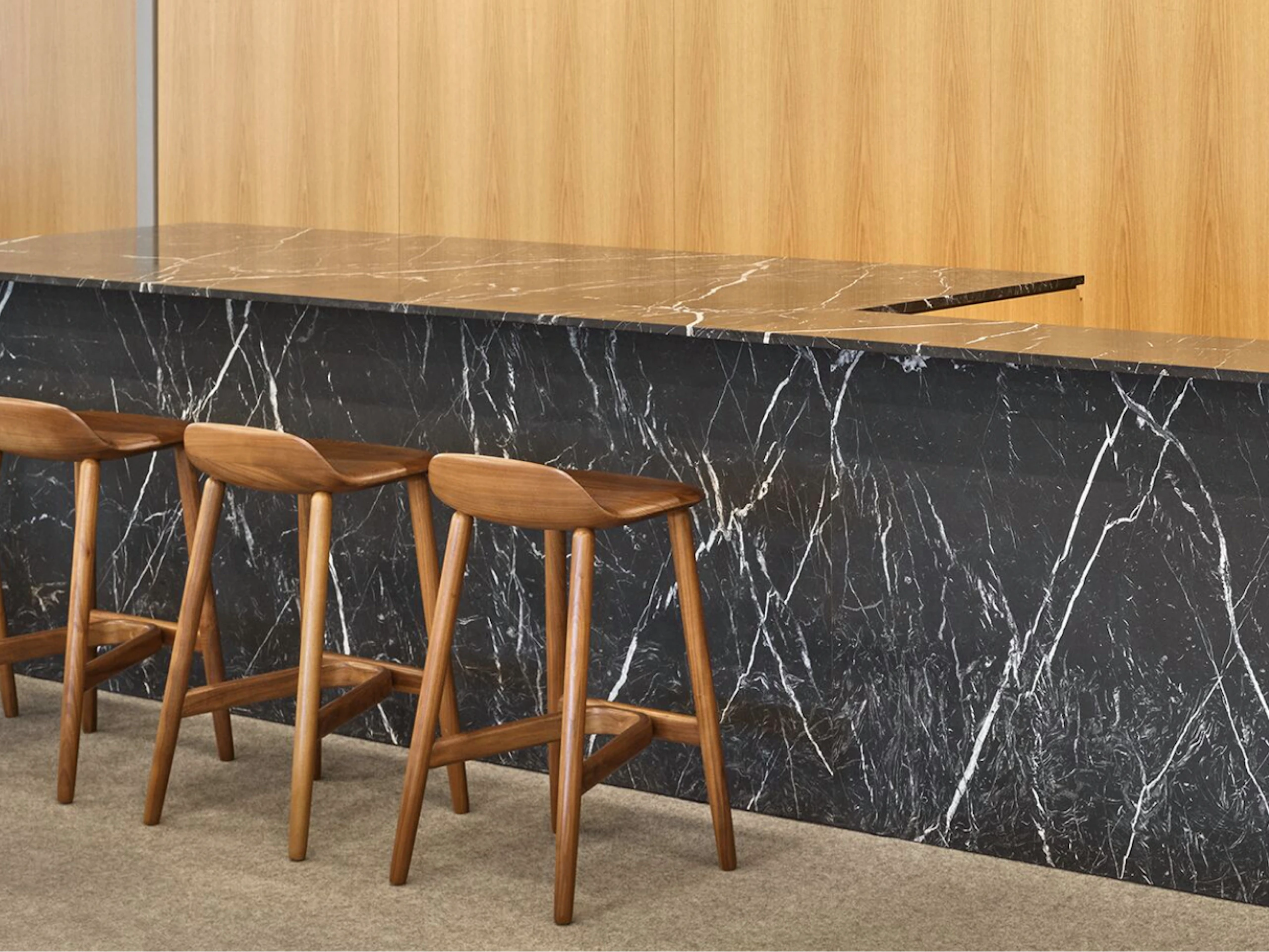 Four brown counter-height stools at a dark grey and white counter