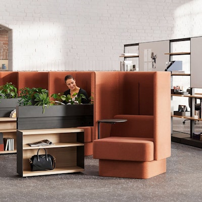 A person working at a computer in a private office setting furnished with Geiger Taper Chairs, a Knoll Grasshopper Table, Saarinen Executive Chairs, and Saarinen Tulip Stools.