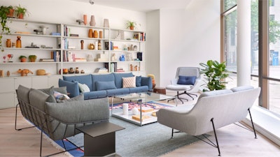 Collection of sofas, a lounge chair and side tables in front of a large bookcase.