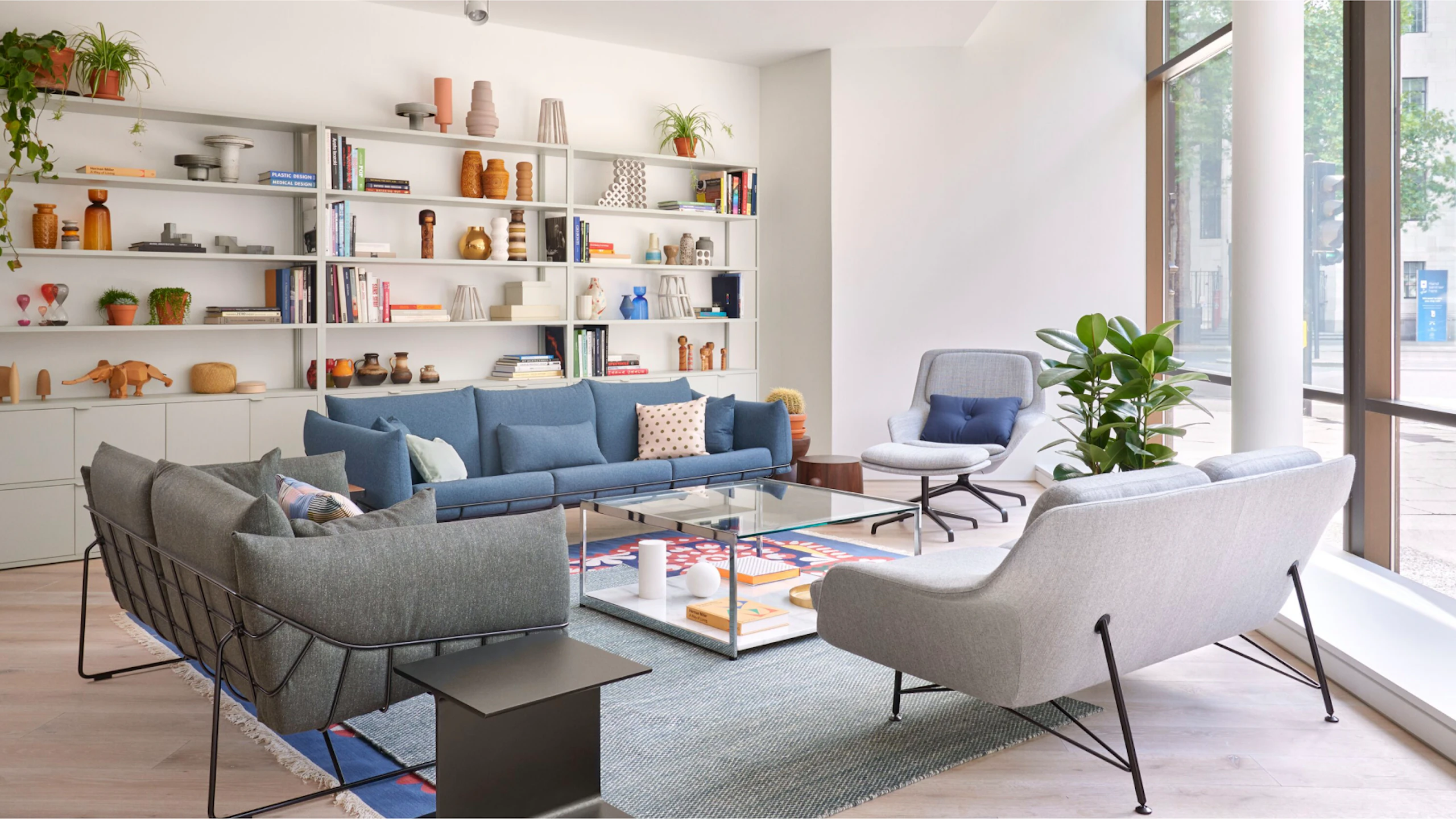 Collection of sofas, a lounge chair and side tables in front of a large bookcase.