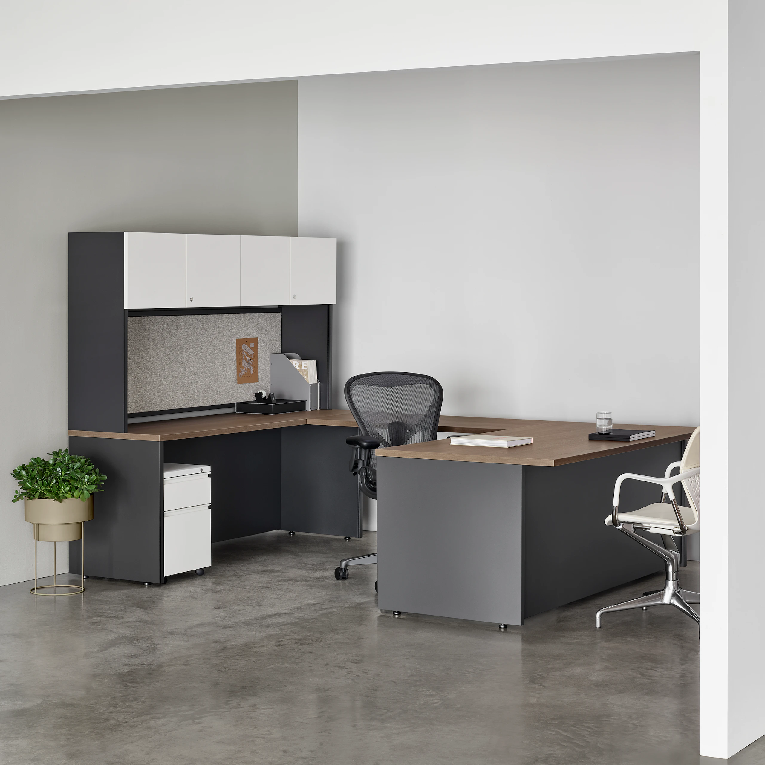 A dark gray Canvas Metal Desk in a private office with white storage, dark wood surfaces, and an Aeron Chair.