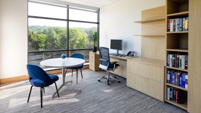 A private office furnished with Saarinen executive chairs, Life chairs, and a Reff private office system overlooking luscious green trees