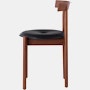 Profile view of a walnut Comma Chair with a seat pad.