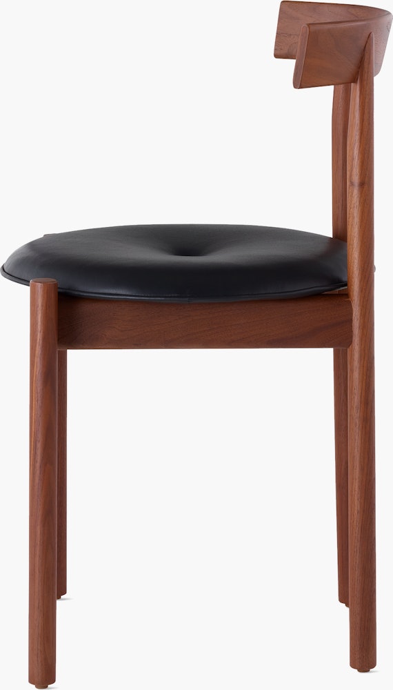 Profile view of a walnut Comma Chair with a seat pad.
