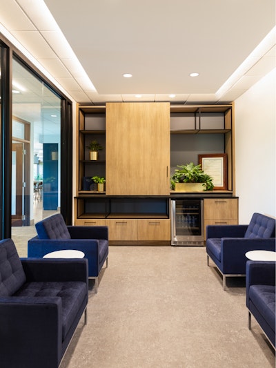 A communal seating area with a large amount of wooden shelving on one wall and several Florence Knoll Lounge Chairs
