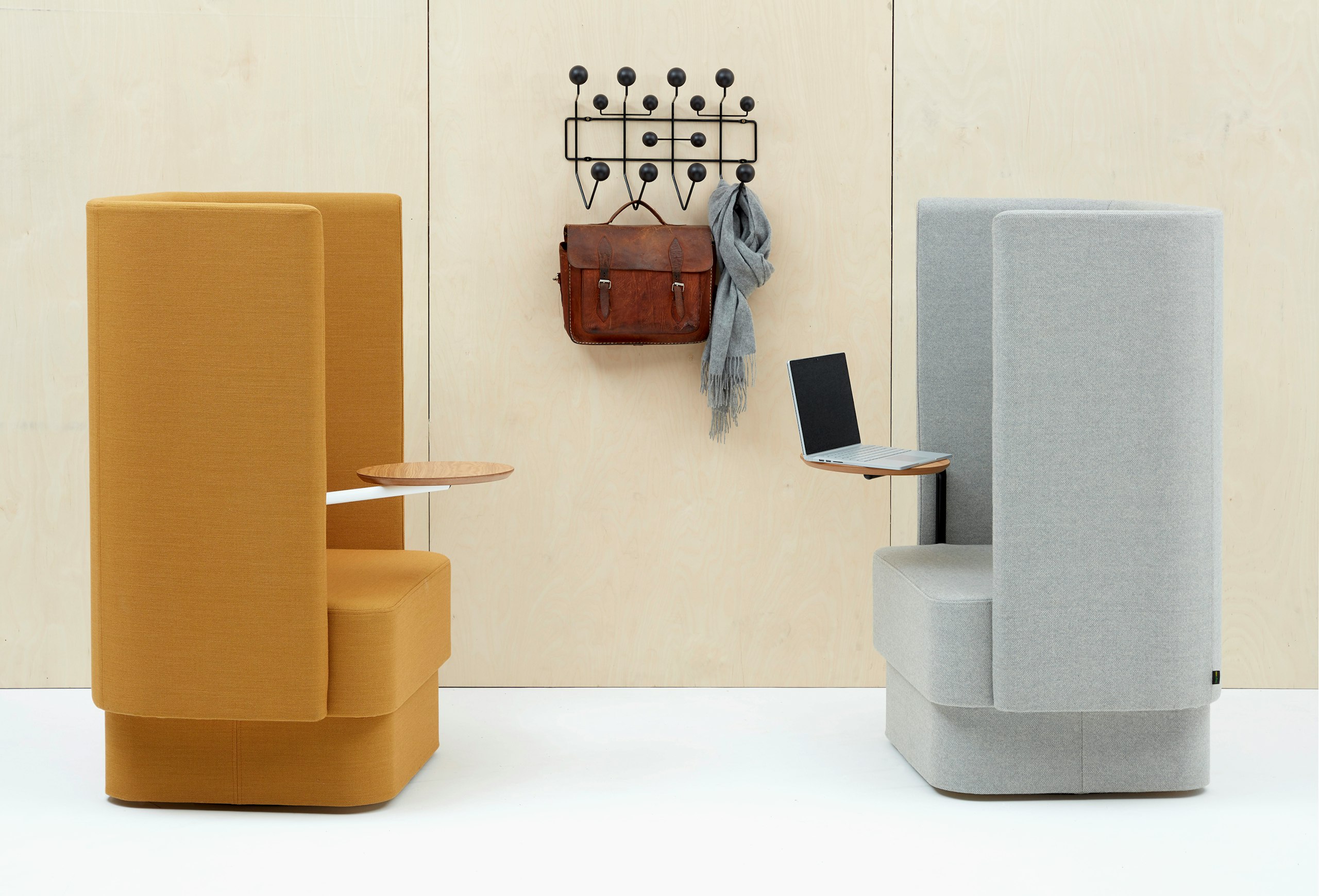 Two high back Pullman Chairs facing each other, one upholstered in yellow fabric and the other in grey fabric. Both with upholstered plinths and oak veneer tablet arms.