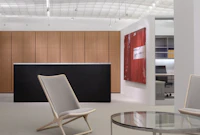 A beige Scissor Chair complements a round Metal Series coffee table in a contemporary reception space.