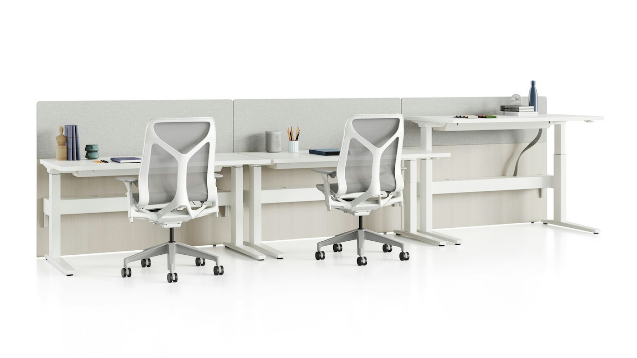 Standing desk system, Renew Link, with rectangular work surfaces, privacy screens, and Cosm Chairs. One of three desks is raised to standing height.