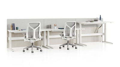 Standing desk system, Renew Link, with rectangular work surfaces, privacy screens, and Cosm Chairs. One of three desks is raised to standing height.