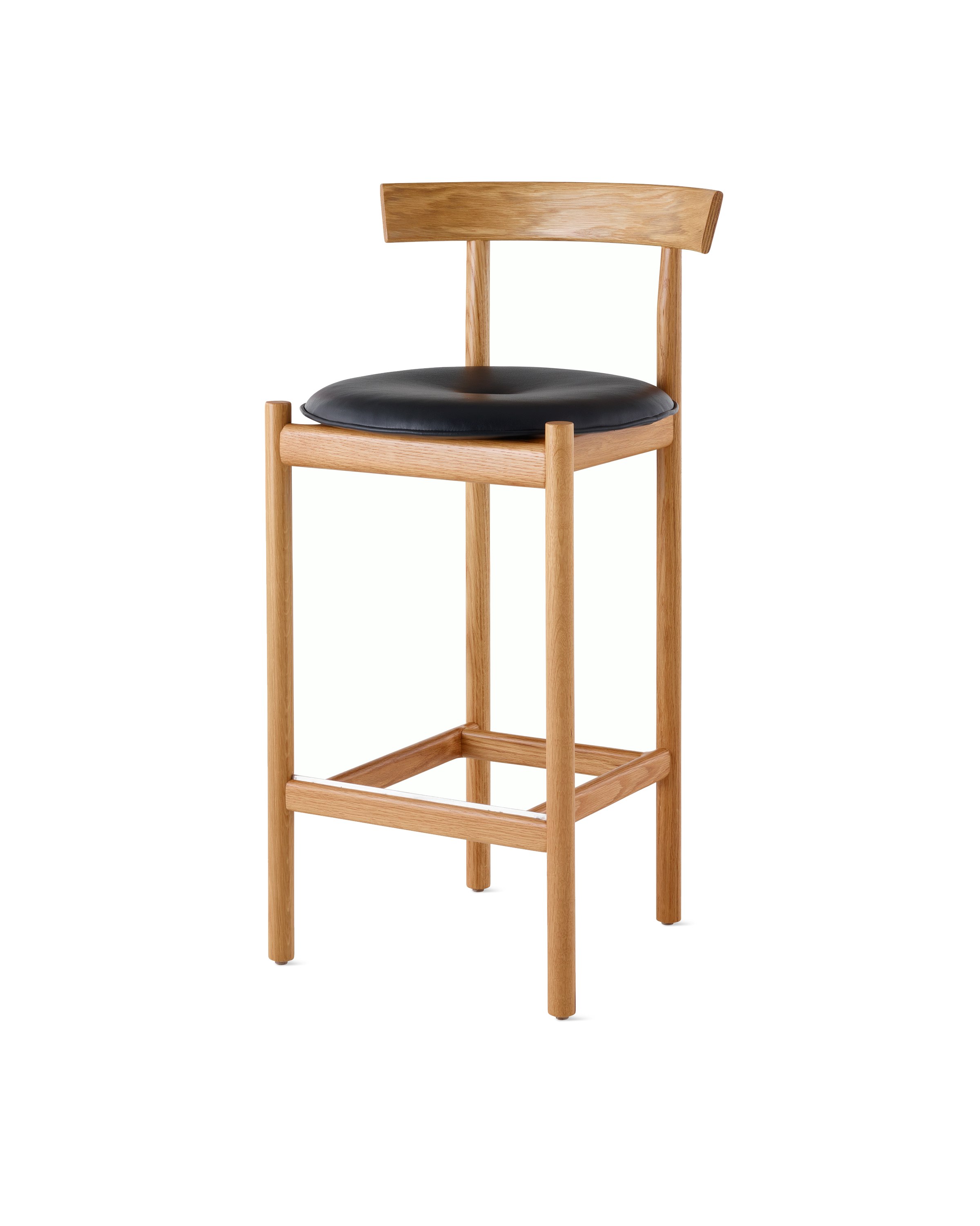 An oak Comma Stool with a seat pad, viewed from the front at an angle.