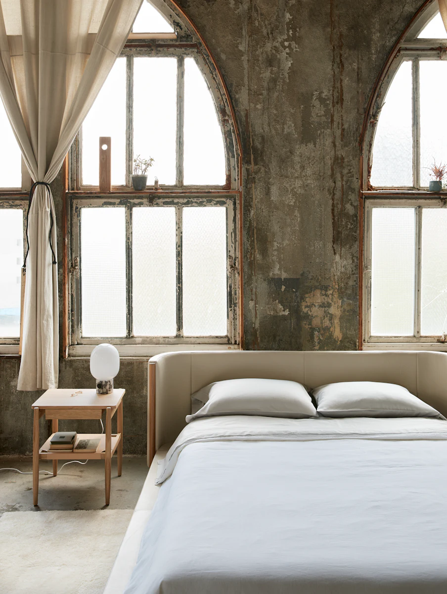 Close-up of white padded bed corner with wooden post.