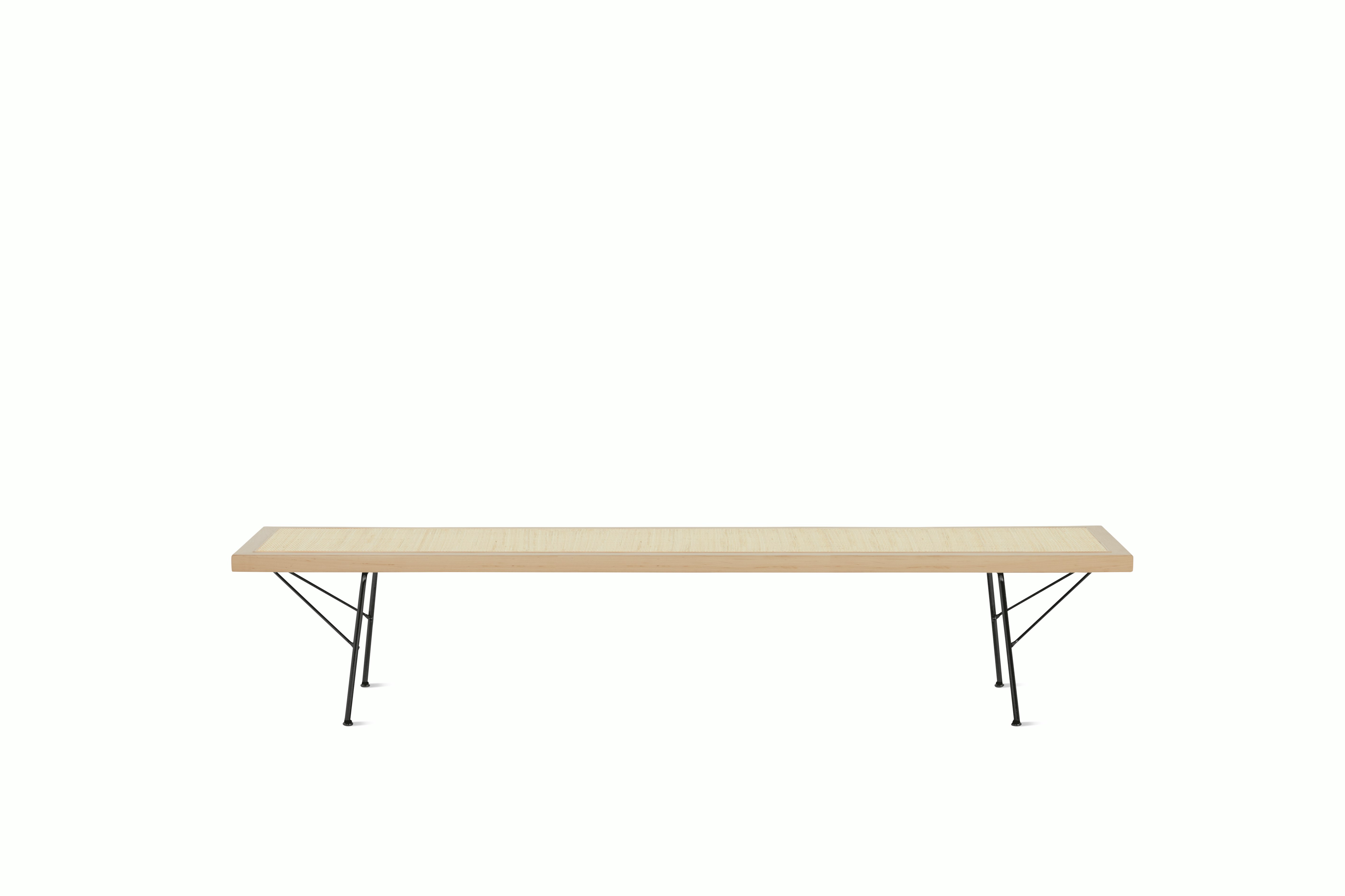 A Nelson Cane Bench with a maple frame and black metal legs, viewed from the long side.