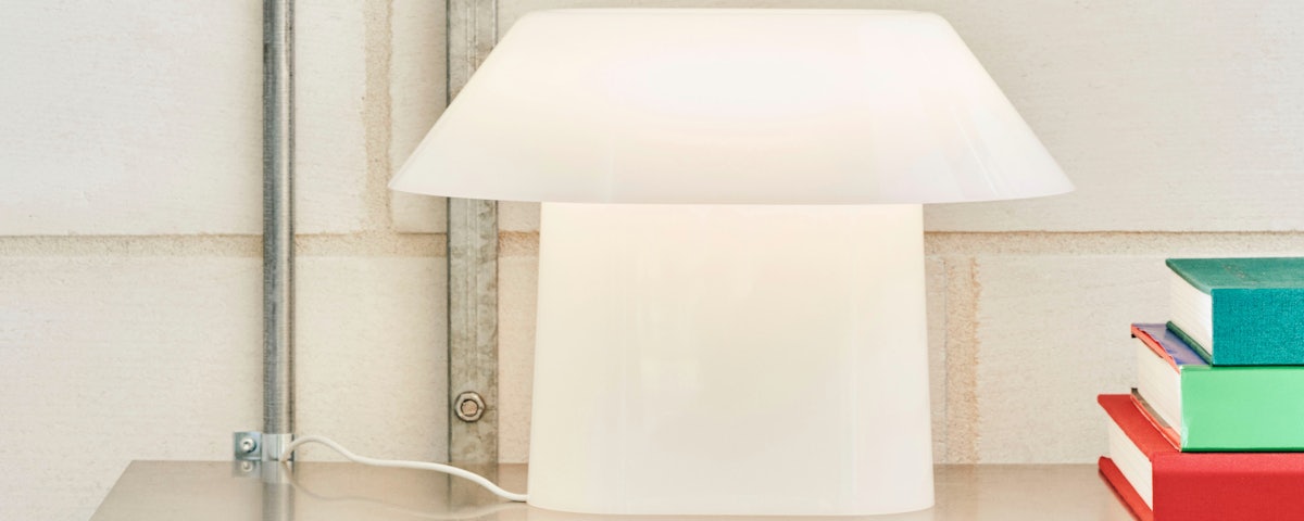 Drome Table Light on an industrial metal bookshelf with books