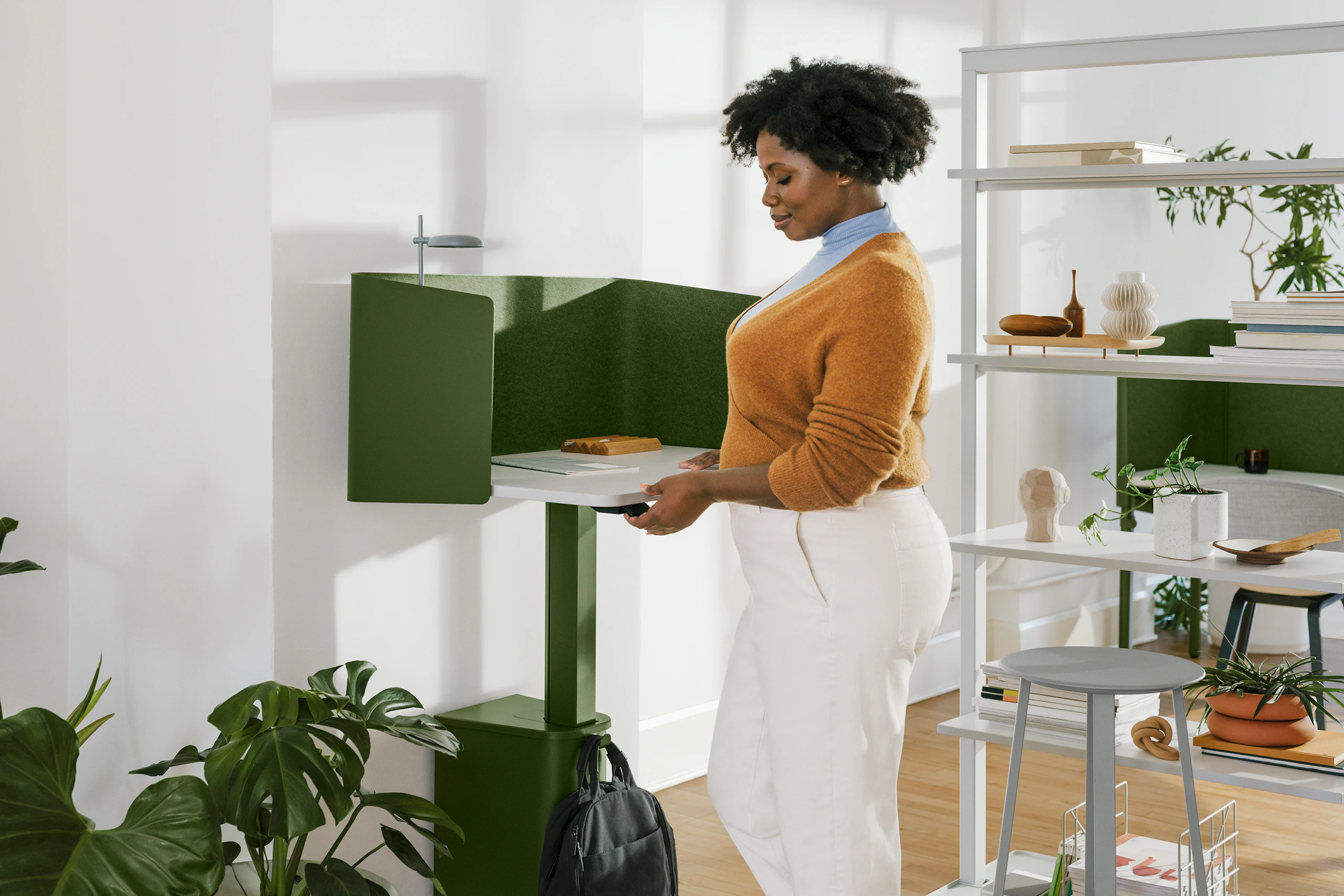 A woman standing at a green, single OE1 Micro Pack with a grey OE1 Agile Wall with full shelves and a green OE1 Nook in the background.