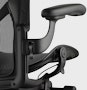 Black matte Aeron Chair on a white background, detailed view of arm height adjustment feature.