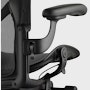 Black matte Aeron Chair on a white background, detailed view of arm height adjustment feature.