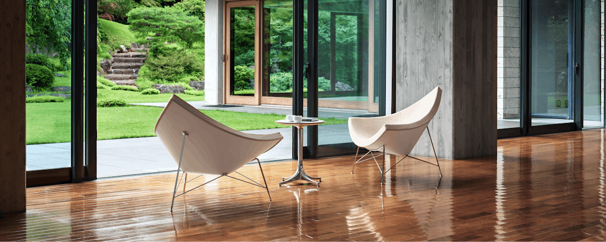 Two Nelson Coconut Lounge Chairs with a Nelson Pedestal table in open room setting