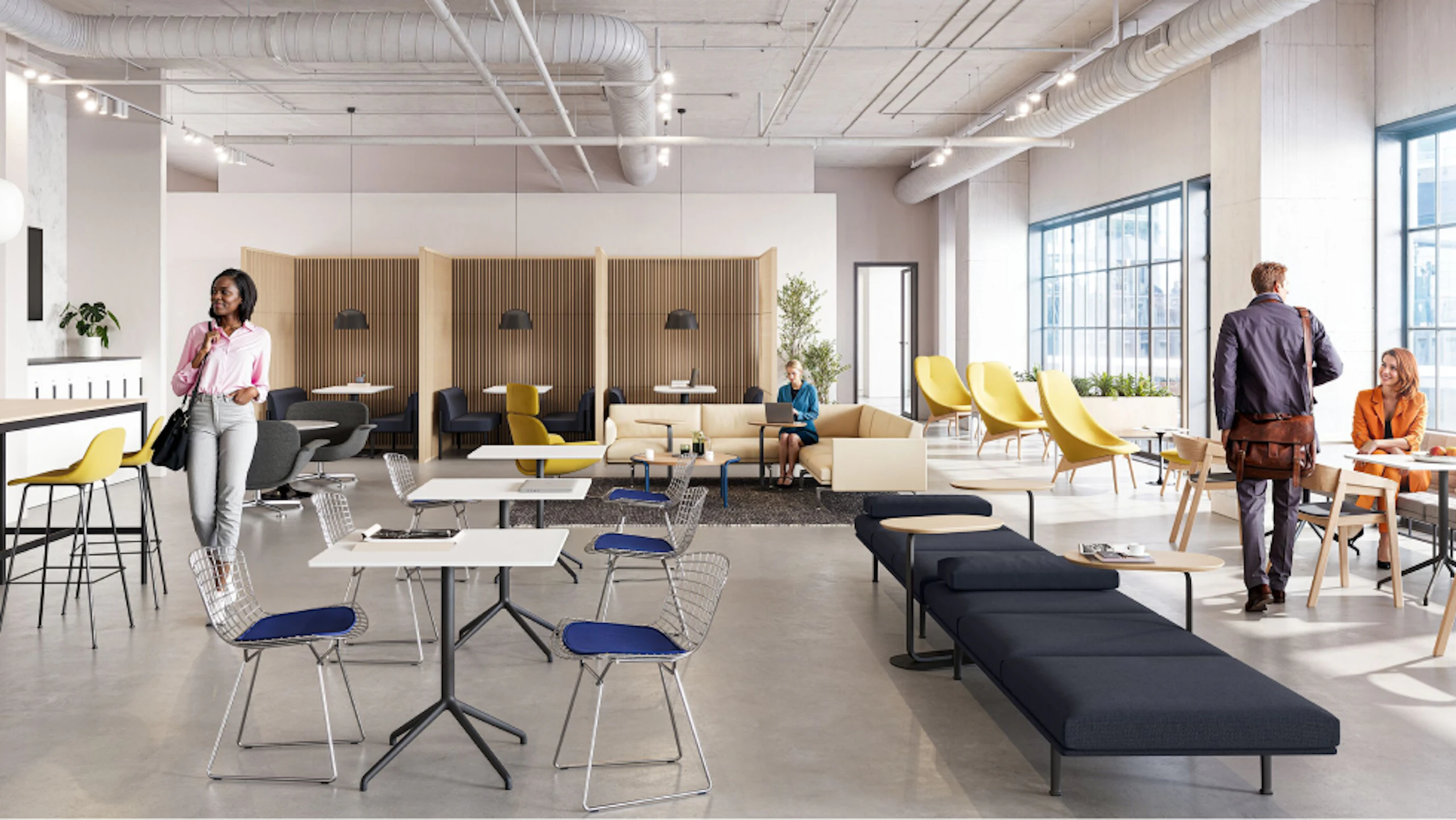 A brightly lit community setting featuring four people utilising a variety of colourful seating options including the HAY Uchiwa Lounge Chair, Muuto Base Tables and Muuto Still Cafe Tables