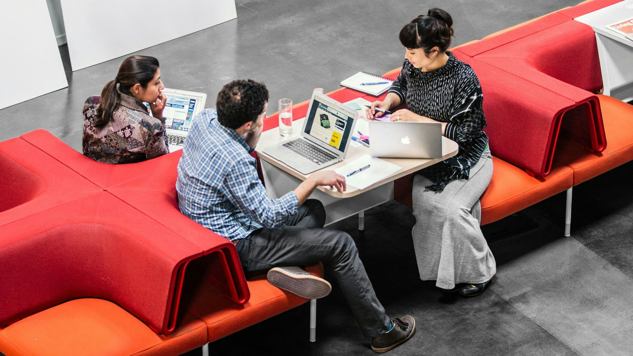 Employees work and talk amidst an open office design.