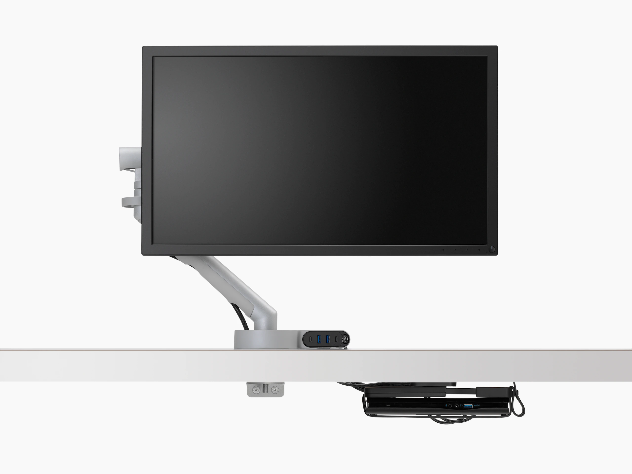 Front view of a screen and monitor arm with power cabling routed through Ondo Connectivity Module connected to the monitor arm and then through to Loop Micro Mount under the desk.