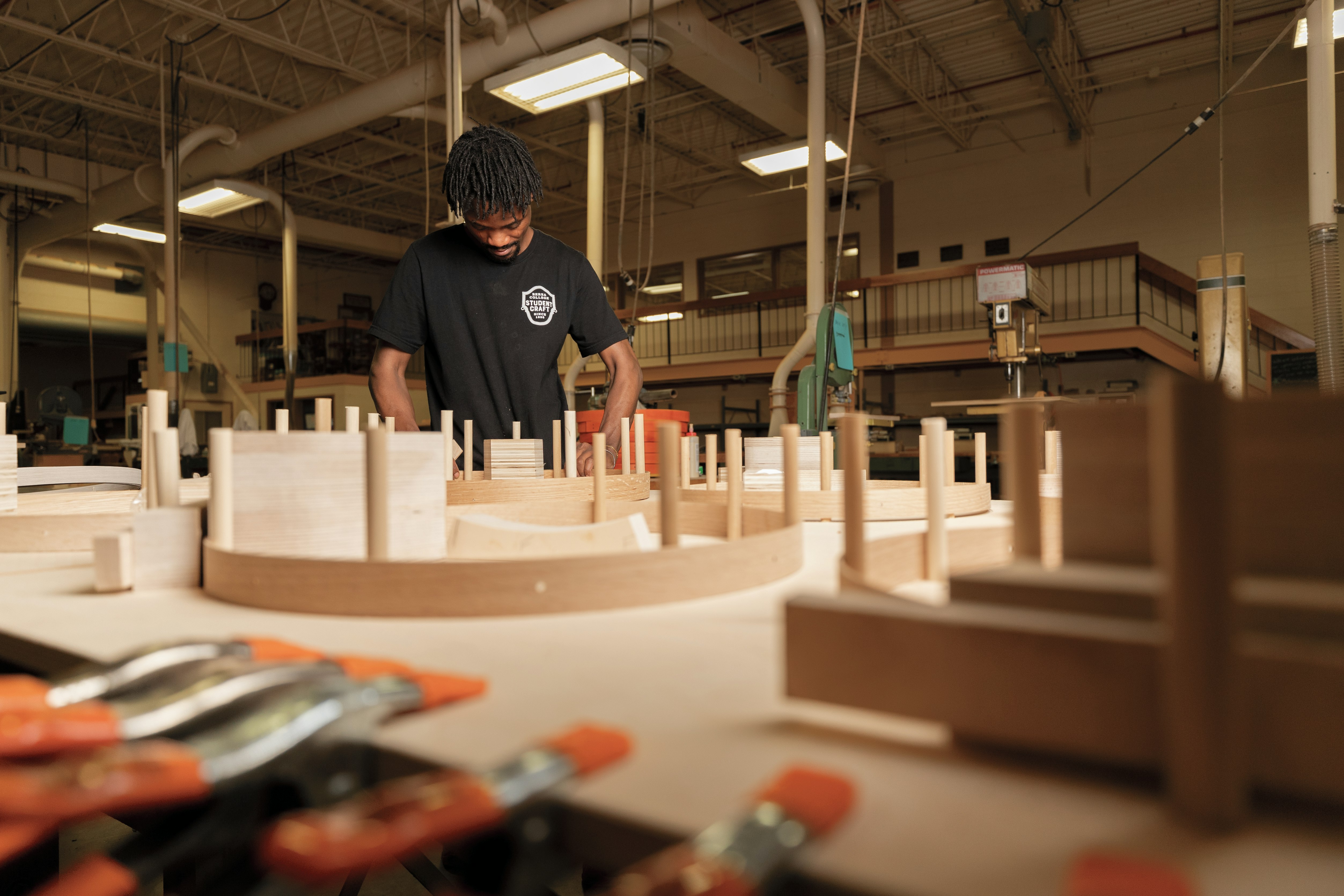 Man bending wooden basket bands around pegs
