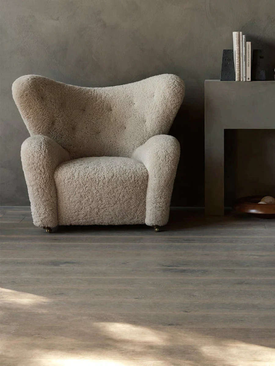 Side view of a cream boucle armchair showing curved back and legs.