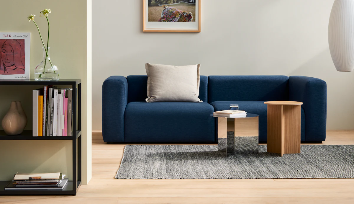 Minimalist living area with gray chair, window, and small round table with green decor.
