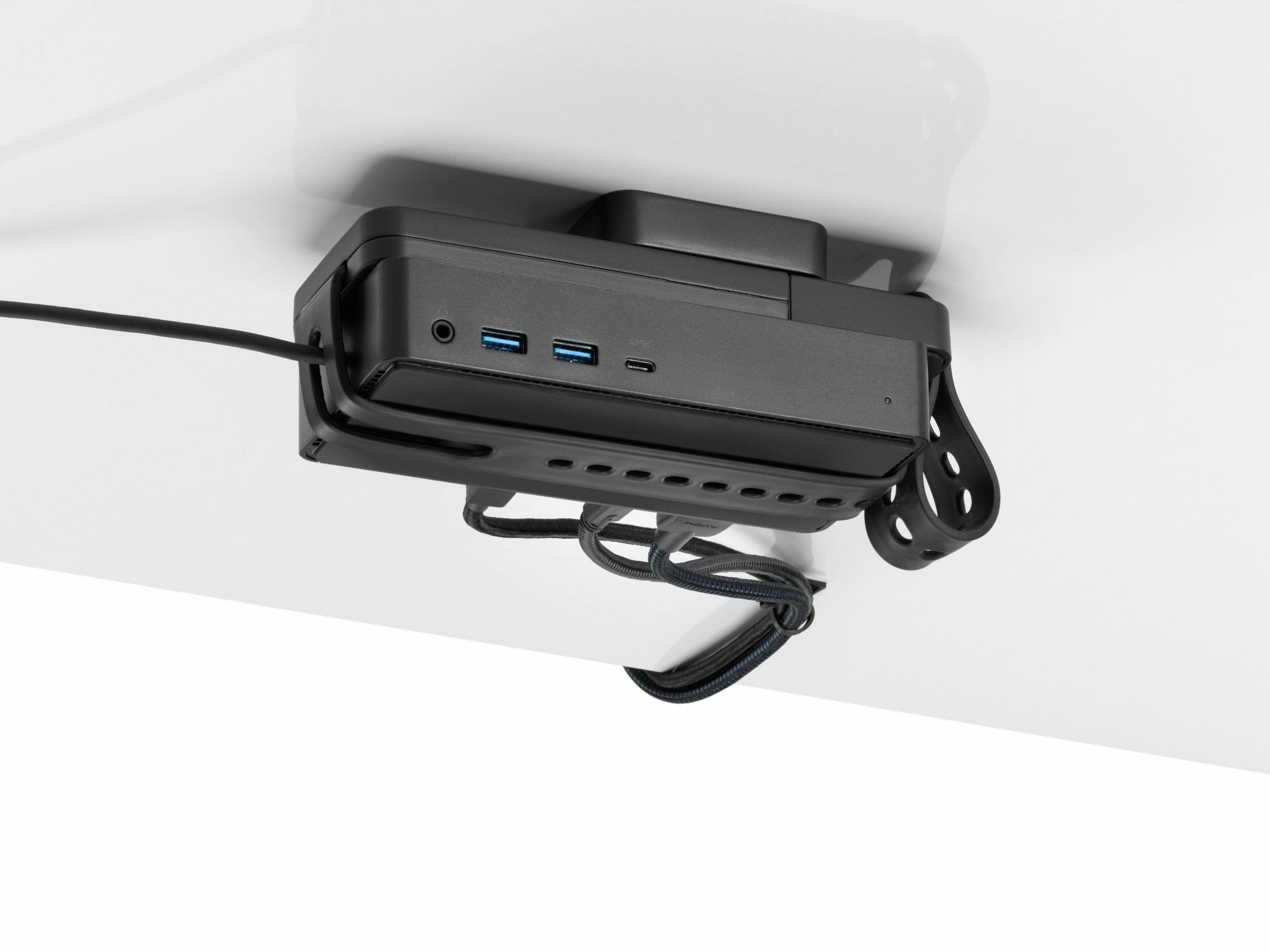 Loop Micro Mount attached under a desk cradling a thin client or power docking station with attached cables that are routed tidily to the edge and above the desk.