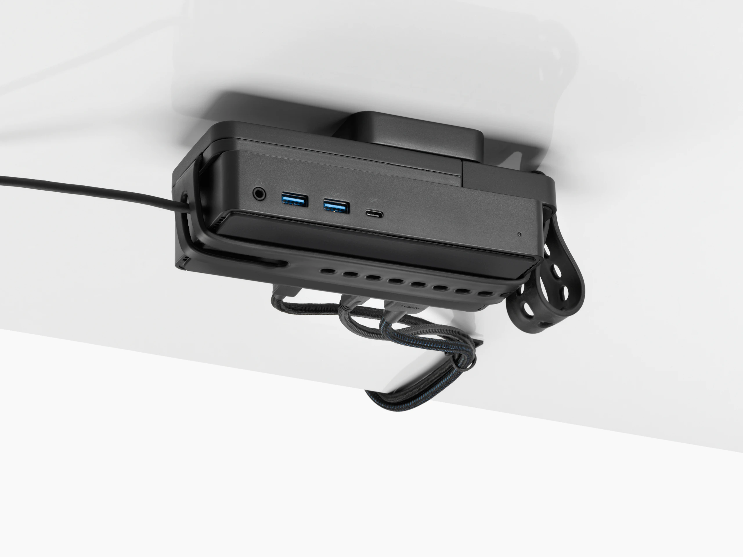 Loop Micro Mount attached under a desk cradling a thin client or power docking station with attached cables that are routed tidily to the edge and above the desk.