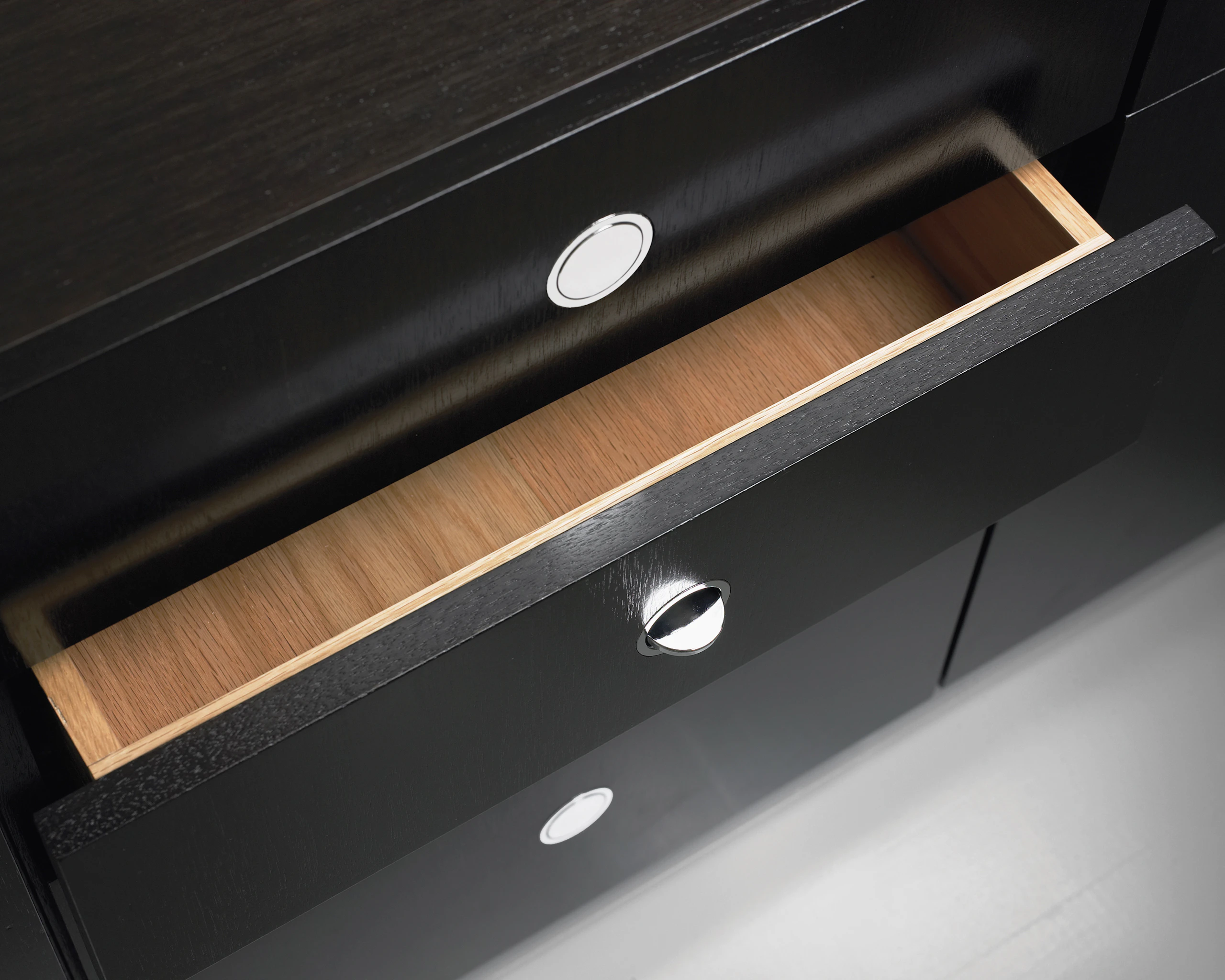 Close-up of an H Frame Storage credenza, showing a slightly open drawer and a chrome flip pull.