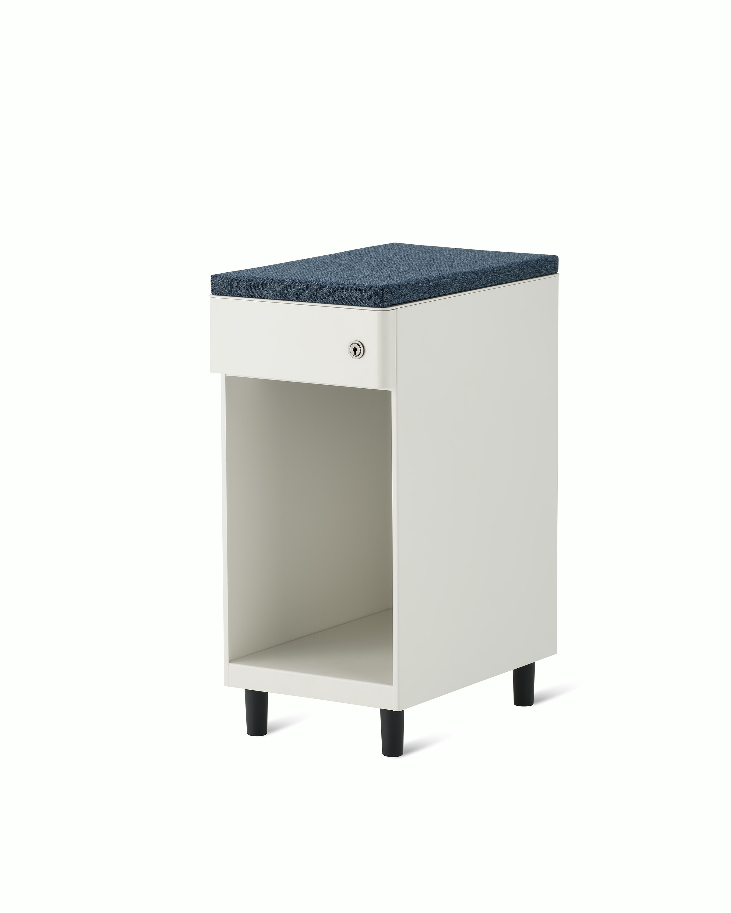 Slim, white storage pedestal on black feet with a drawer and a lock, a blue cushion top, and opening below drawer for storage.