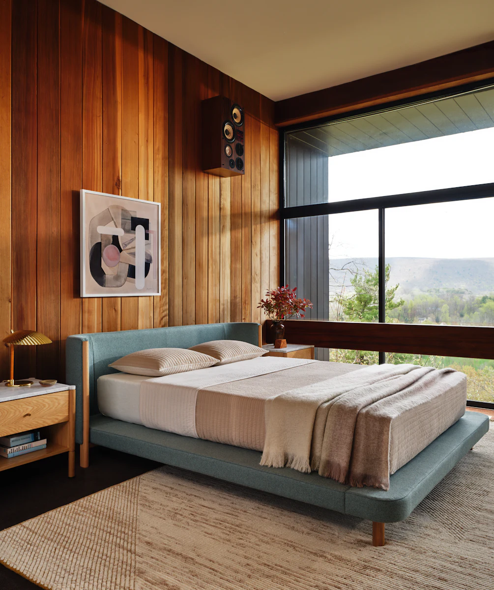 Teal upholstered bed with wooden posts and side table
