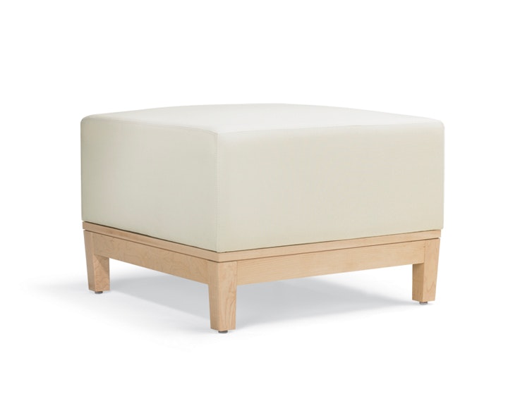 A three-quarter view of a short, ottoman-style Brava Platform Lounge Bench with maple base and white textile.