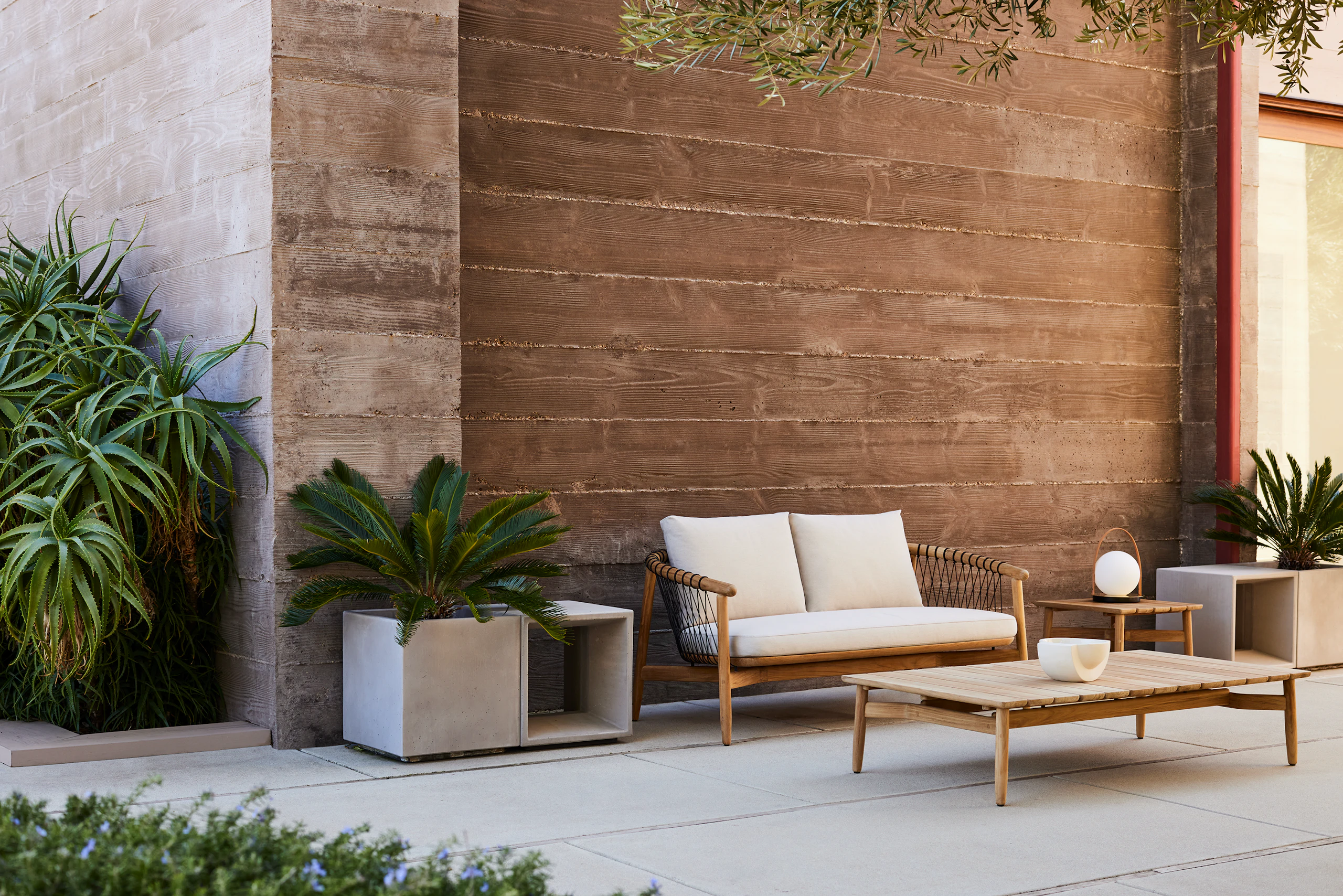 Crosshatch Outdoor Settee with Side Table and Rectangular Coffee Table in an environmental setting.