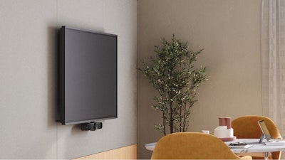 A large TV screen mounted on a wall above orange Saarinen Executive Chairs and a white Knoll Grasshopper Table in a private office setting designed to encourage connection amongst colleagues