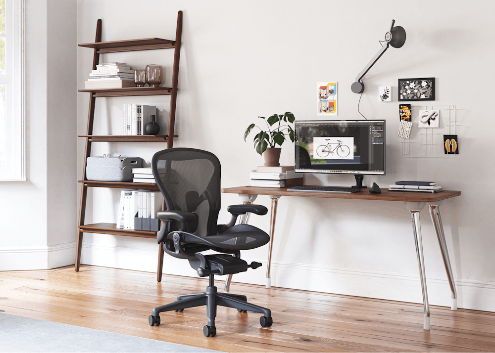 An AbakEnvironments Desk with a walnut top and polised legs, with a graphite Aeron Chair in a light home office setting and Folk Ladder Shelving.