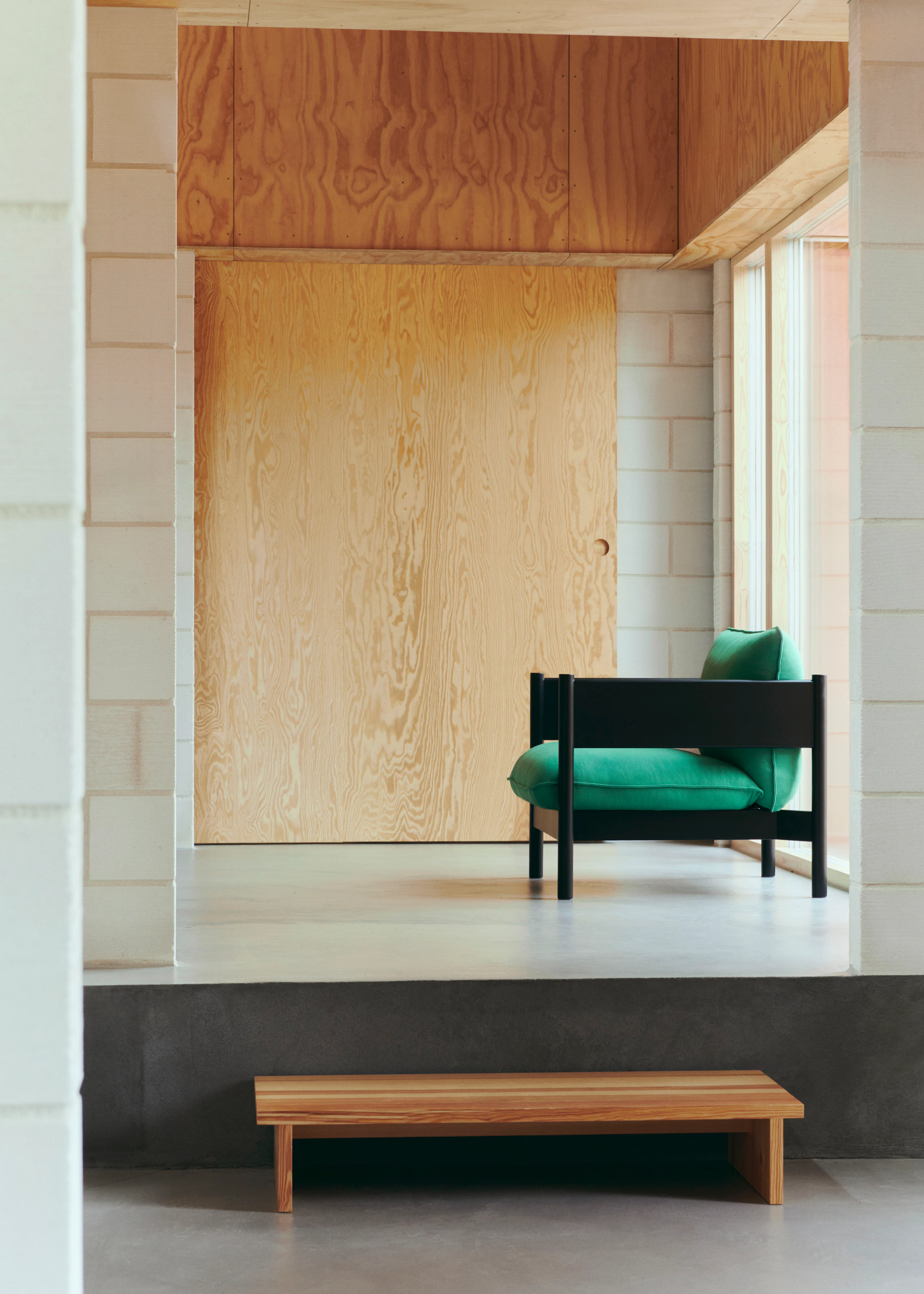 Arbour Club Armchair with black base and green upholstery in a room viewed from the side