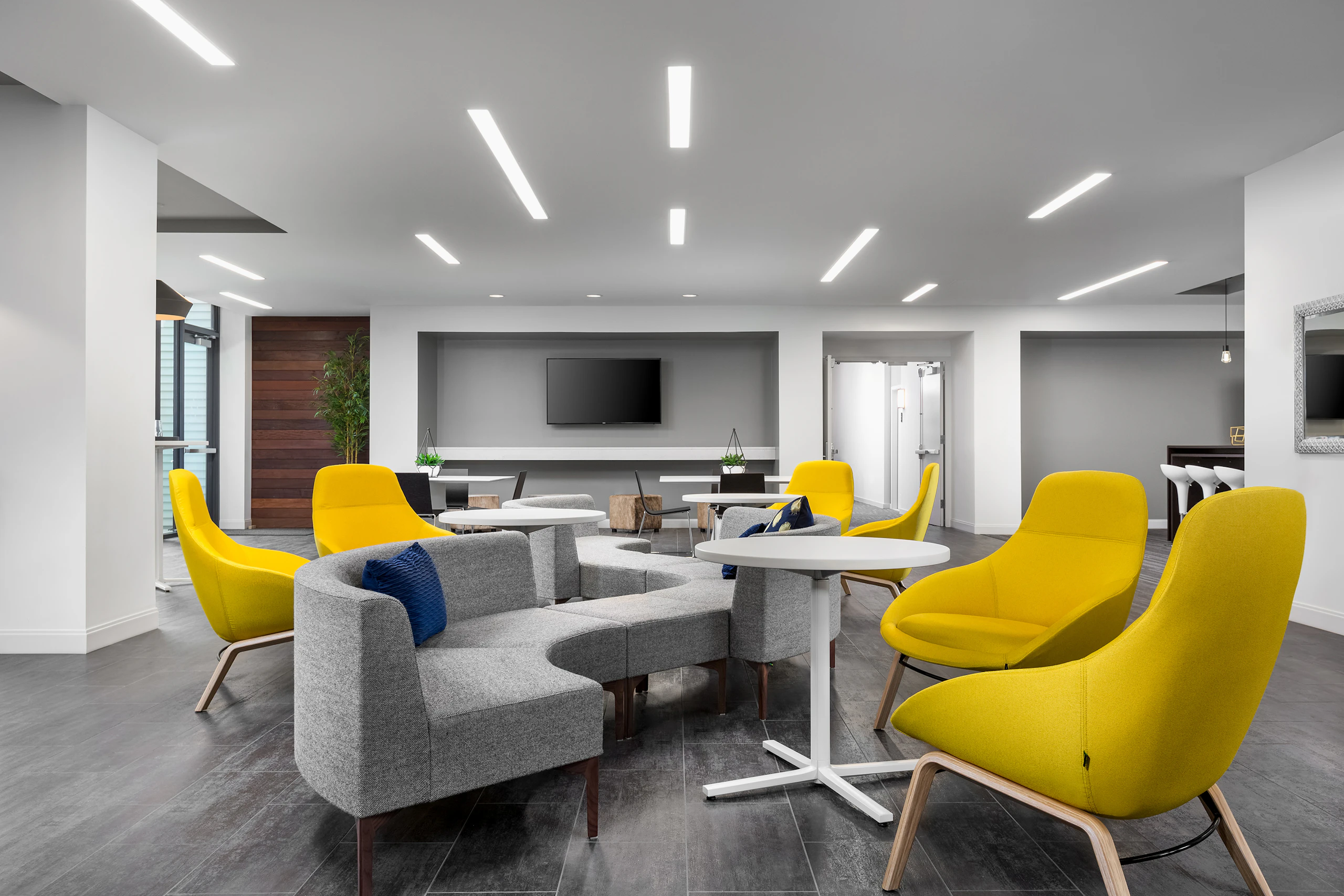 Gray single naughtone Symbol Benches joining Symbol Modular Seating together to snake across the room with yellow Always Lounge Chairs.