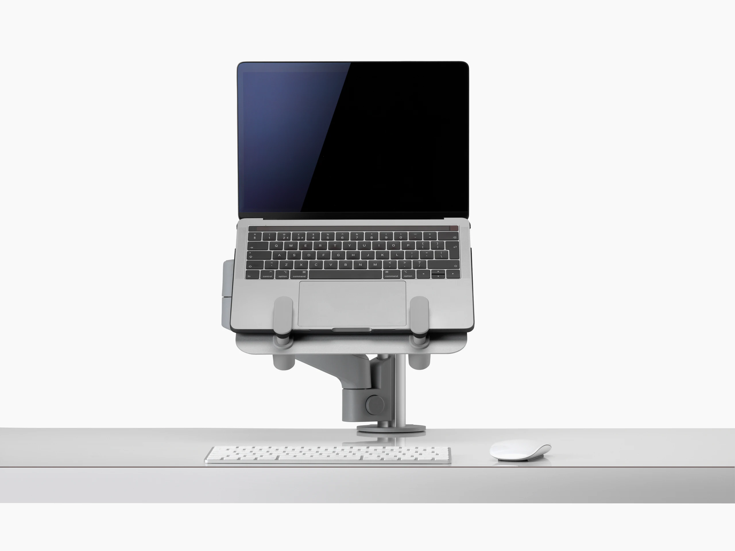 An open laptop raised from a desk and supported by a grey Lima Laptop Mount and Lima Monitor Arm.